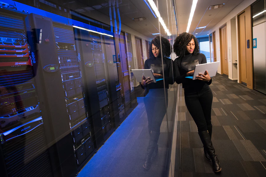 Two IT engineers reviewing infrastructure on a laptop inside a data center aisle